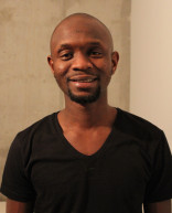 Portrait photo of a Black man wearing a black shirt, facing the camera and smiling.